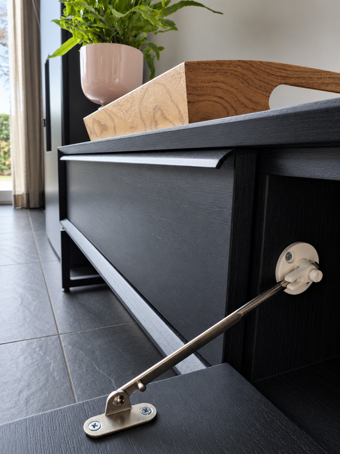 Detail van de geopende klep en het klepmechanisme van het zwarte Ktwo Home tv-meubel